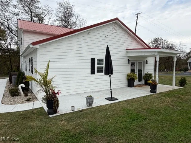 Rear view of property with a yard and a metal roof