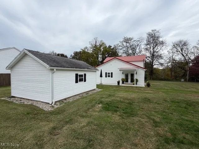 Back of house featuring a yard, an outdoor structure, and a patio area
