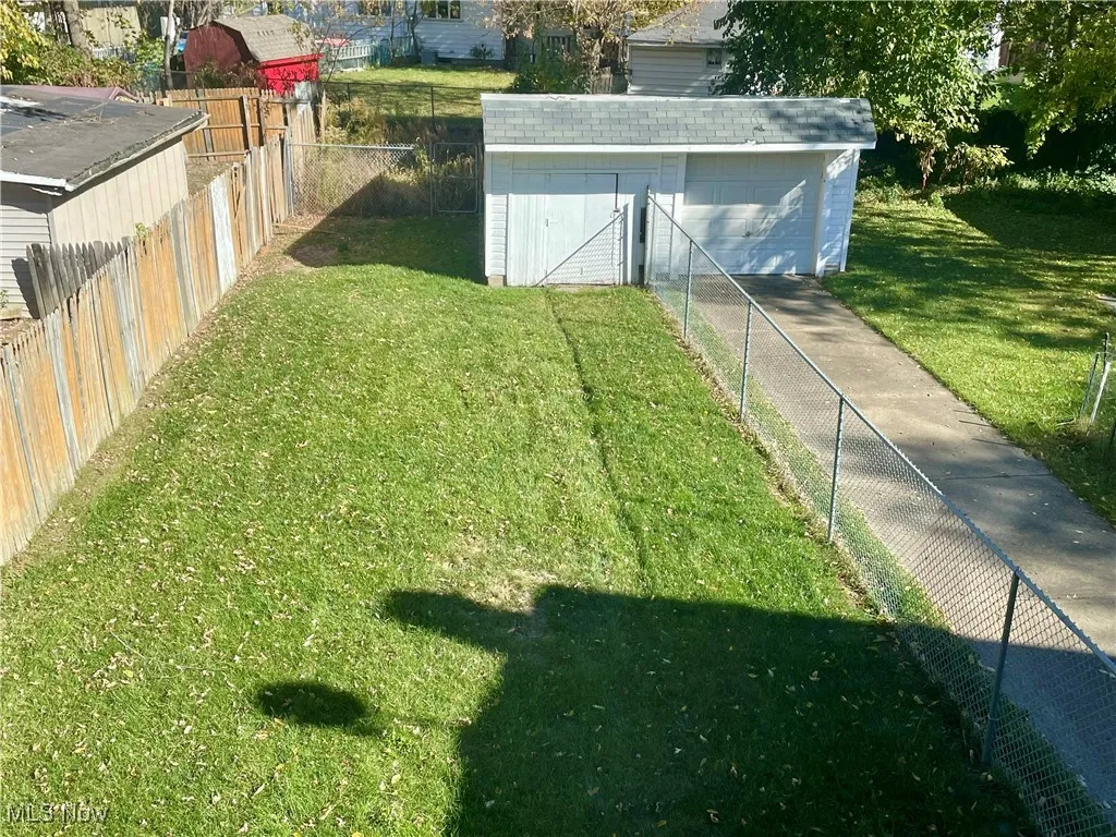 Fenced backyard featuring an outbuilding and a garage