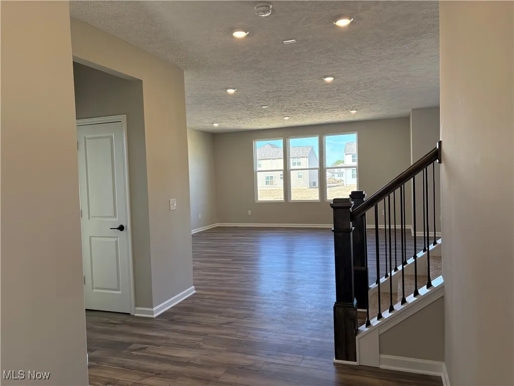 Stairway featuring a textured ceiling and wood finished floors