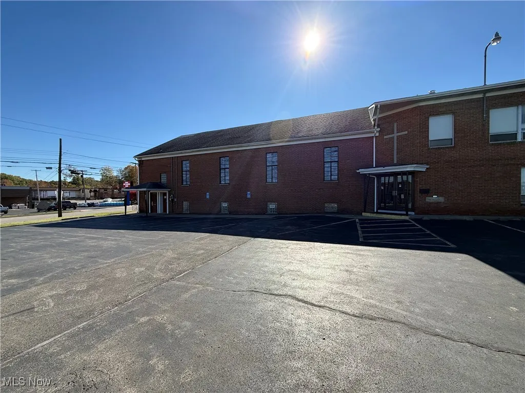 Rear view of property with uncovered parking, a gazebo, and brick siding