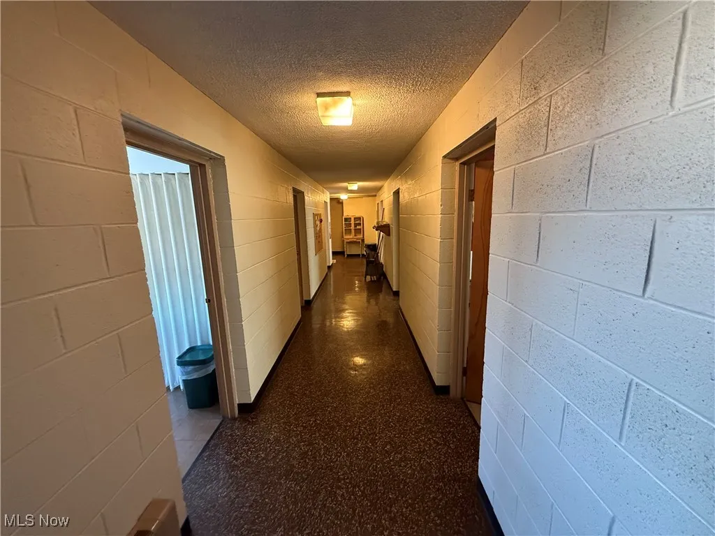 Hallway with concrete block wall and a textured ceiling