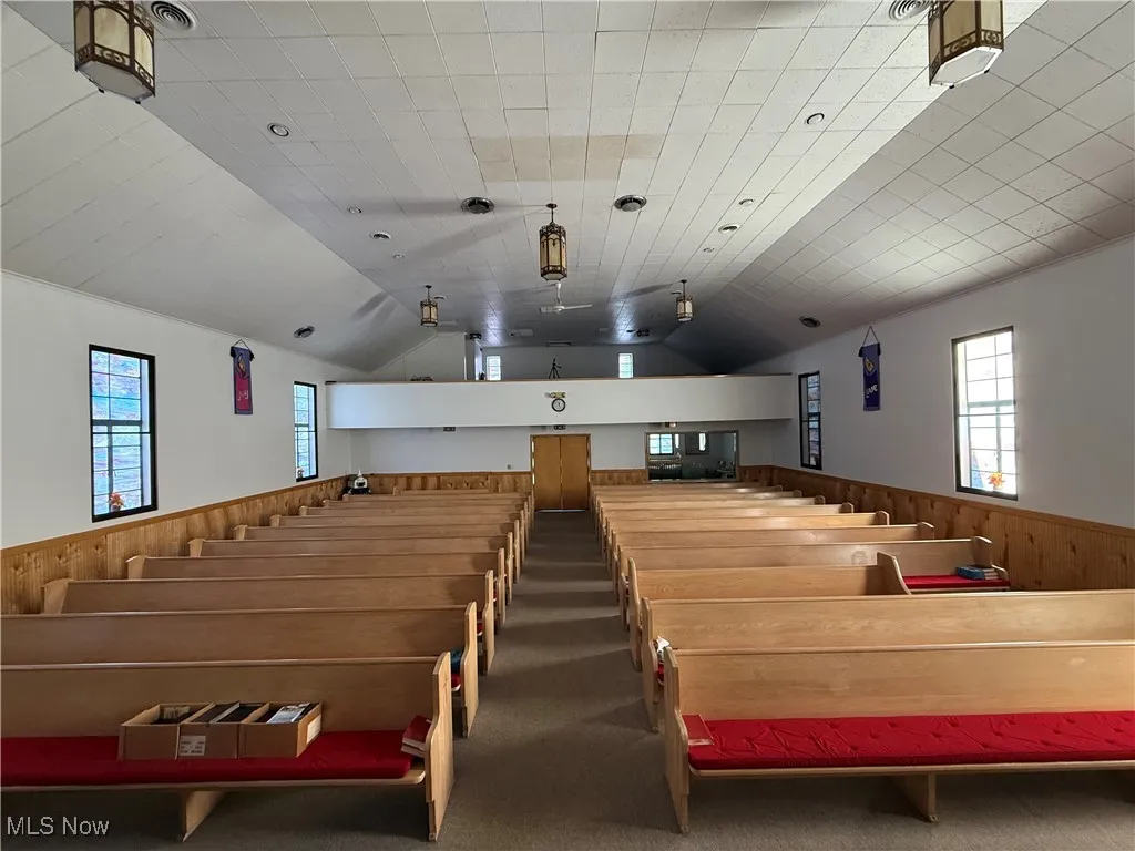 Home theater featuring wooden walls, a wainscoted wall, vaulted ceiling, and dark colored carpet