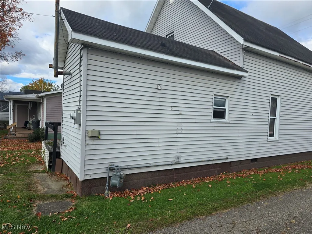 View of side of property featuring roof with shingles and crawl space