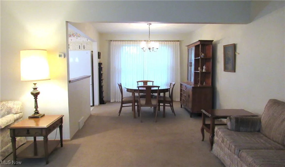 Dining area featuring light colored carpet and a chandelier