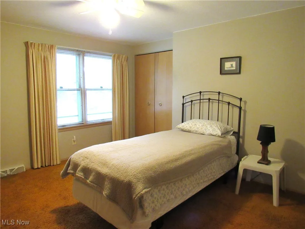 Bedroom featuring dark colored carpet, ceiling fan, and a closet