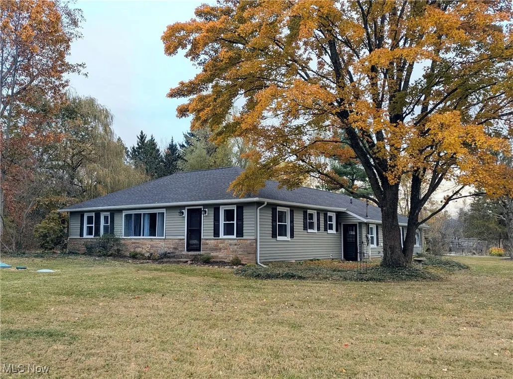 Single story home featuring stone siding and a front yard