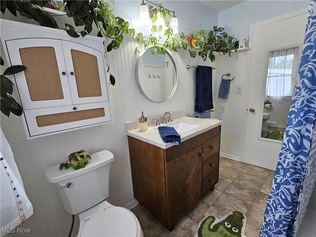 Bathroom featuring vanity, curtained shower, and light tile patterned flooring