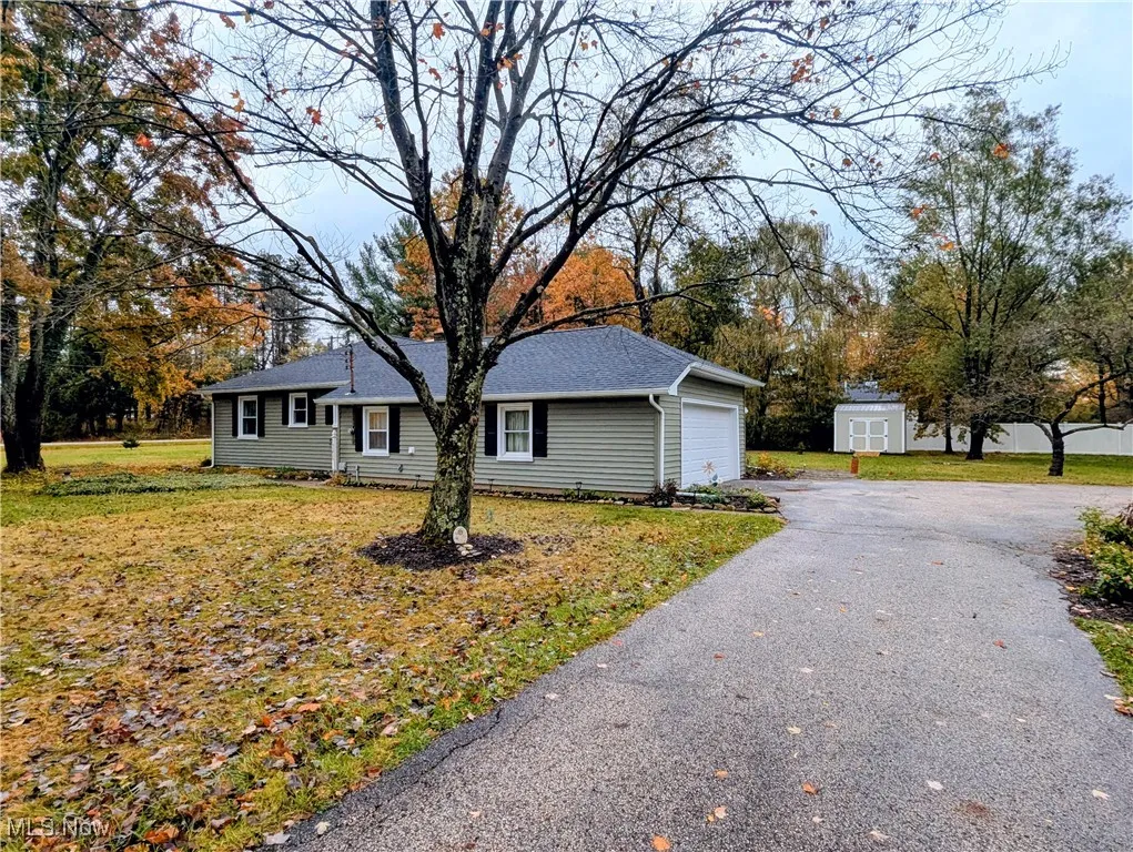 Ranch-style house featuring a front lawn, asphalt driveway, and a garage