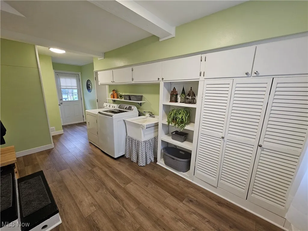 Laundry room with beamed ceiling, dark wood-style floors, washing machine and clothes dryer, and cabinet space