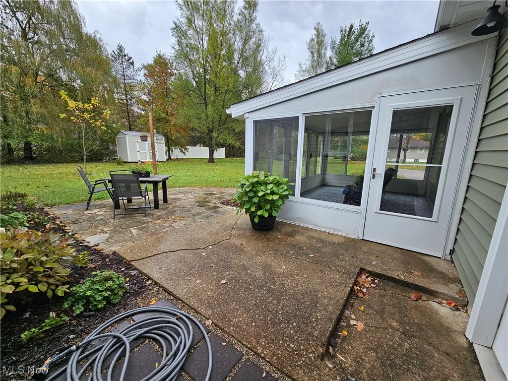 View of patio featuring a sunroom and a shed