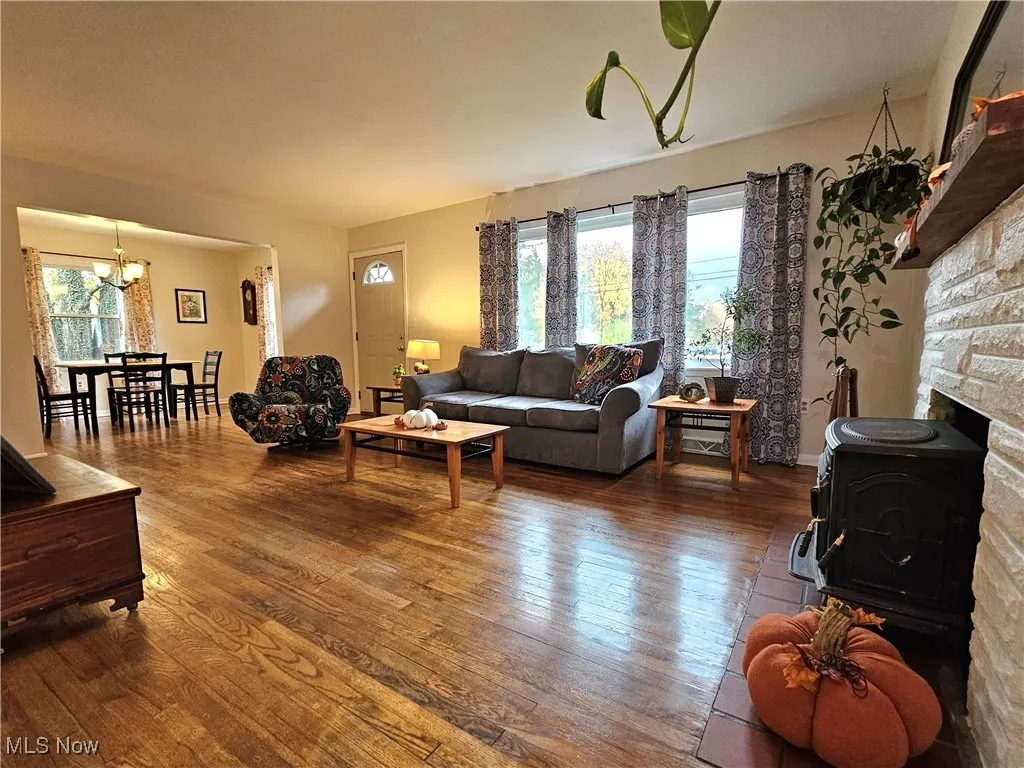 Living room with hardwood / wood-style flooring, a wood stove, and a chandelier