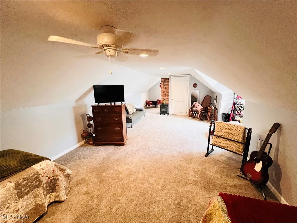 Bonus room with a textured ceiling, lofted ceiling, carpet floors, and ceiling fan