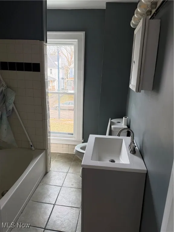 Full bath featuring vanity, light tile patterned flooring, and  shower combination