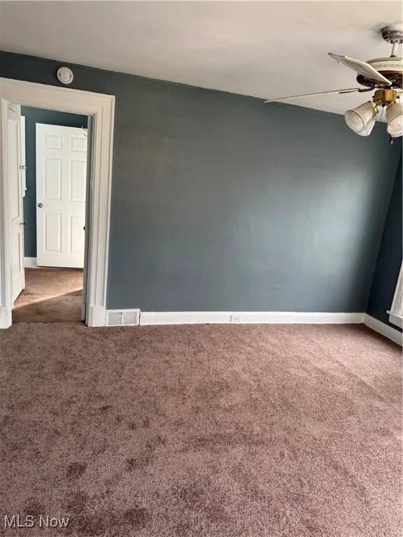 Empty room featuring carpet floors and a ceiling fan