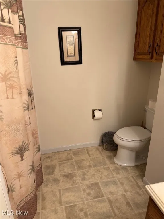 Full bathroom with curtained shower and light tile patterned flooring