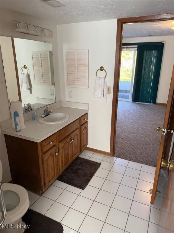 Bathroom with a textured ceiling, light tile patterned floors, and vanity