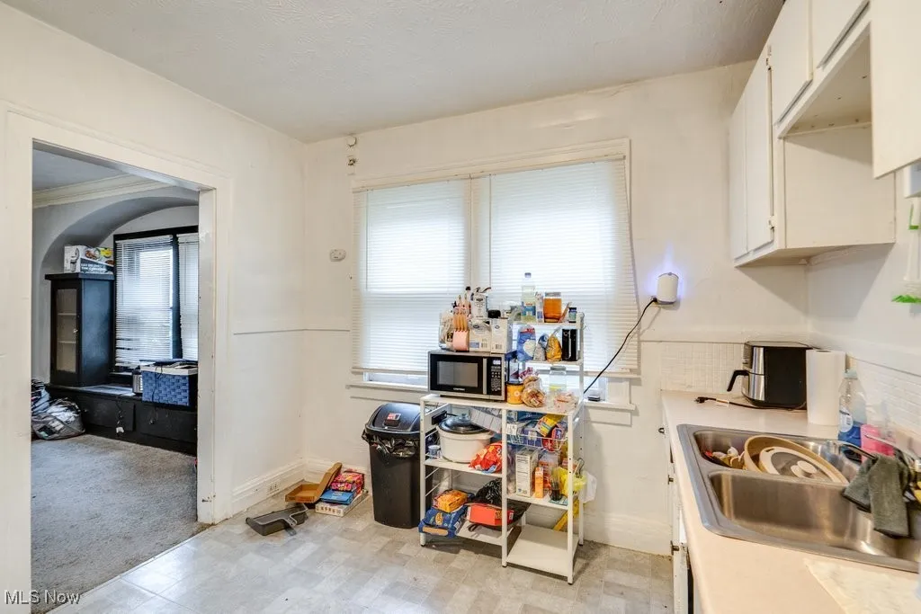 Kitchen featuring light countertops, white cabinets, light floors, black microwave, and light colored carpet