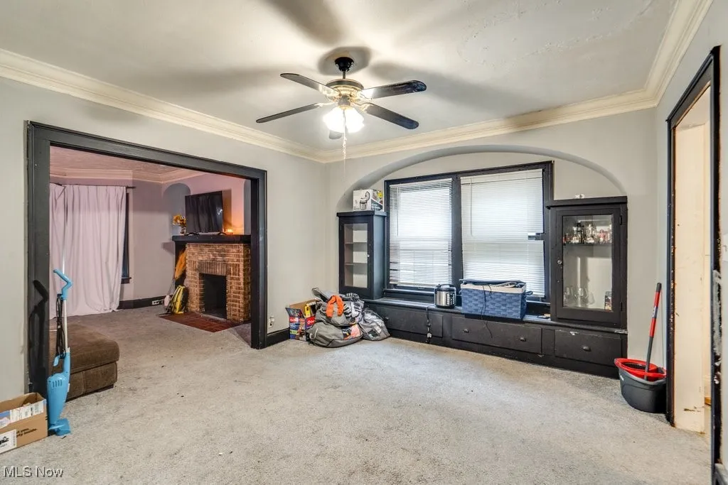 Playroom with crown molding, a fireplace, carpet floors, and ceiling fan