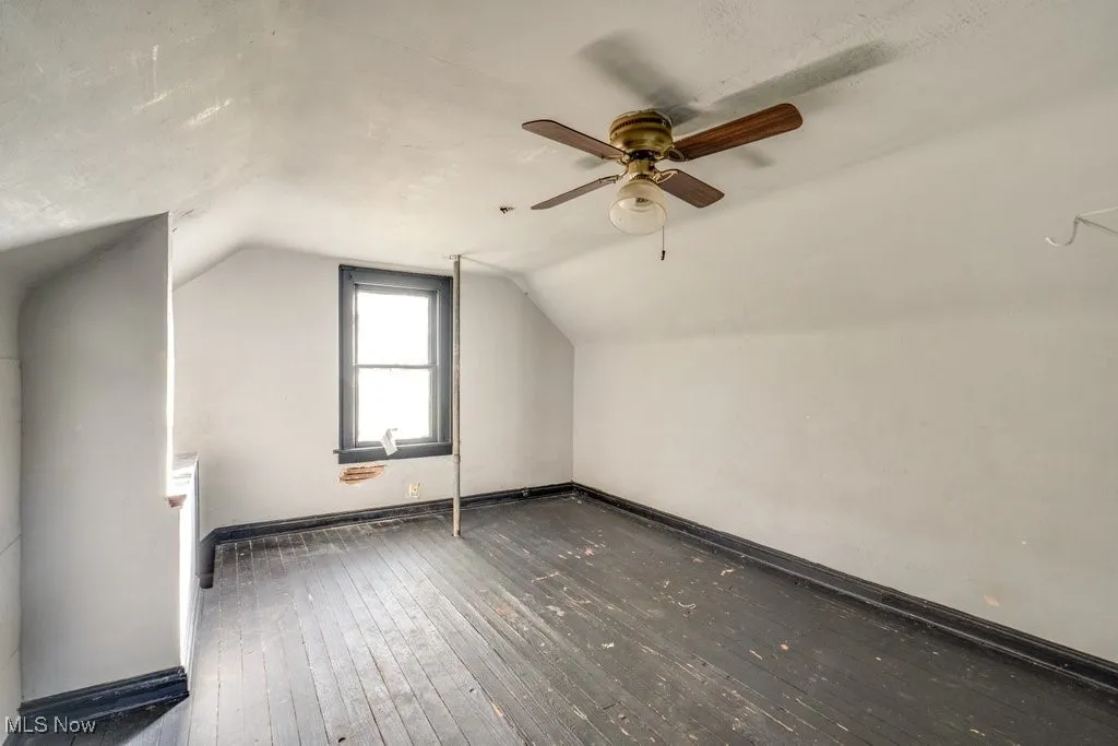 Additional living space with dark wood-type flooring and vaulted ceiling