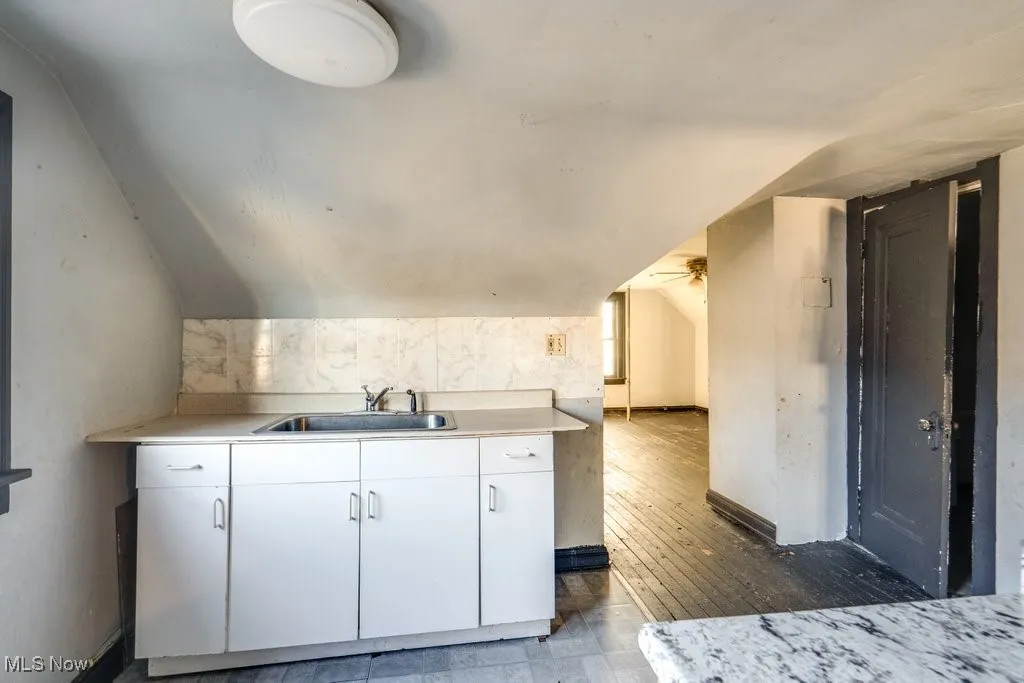 Kitchen with light countertops, white cabinetry, and lofted ceiling