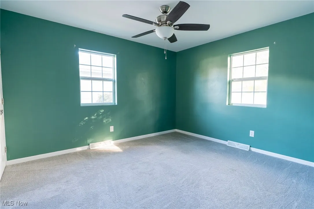 Carpeted empty room featuring baseboards and ceiling fan