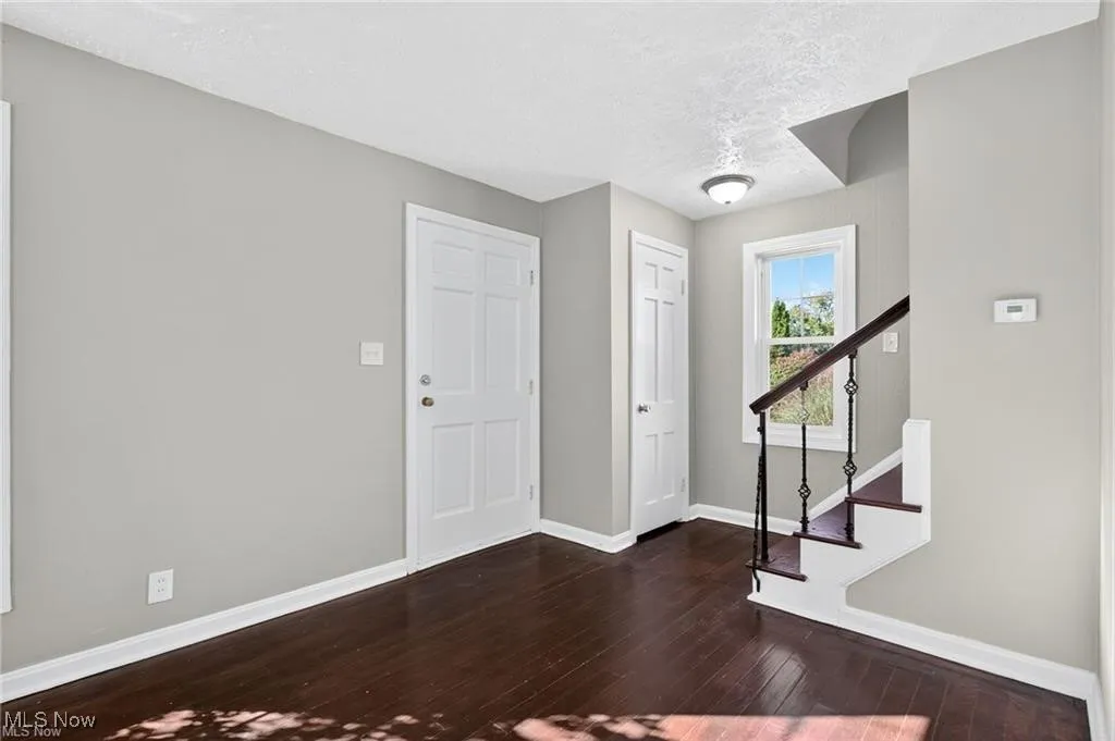 Entrance foyer featuring a textured ceiling, dark wood-style floors, and stairway