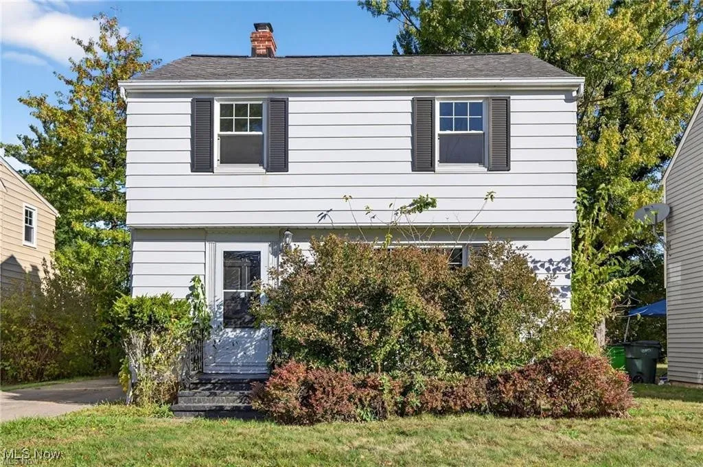 Colonial inspired home featuring a chimney and a front lawn