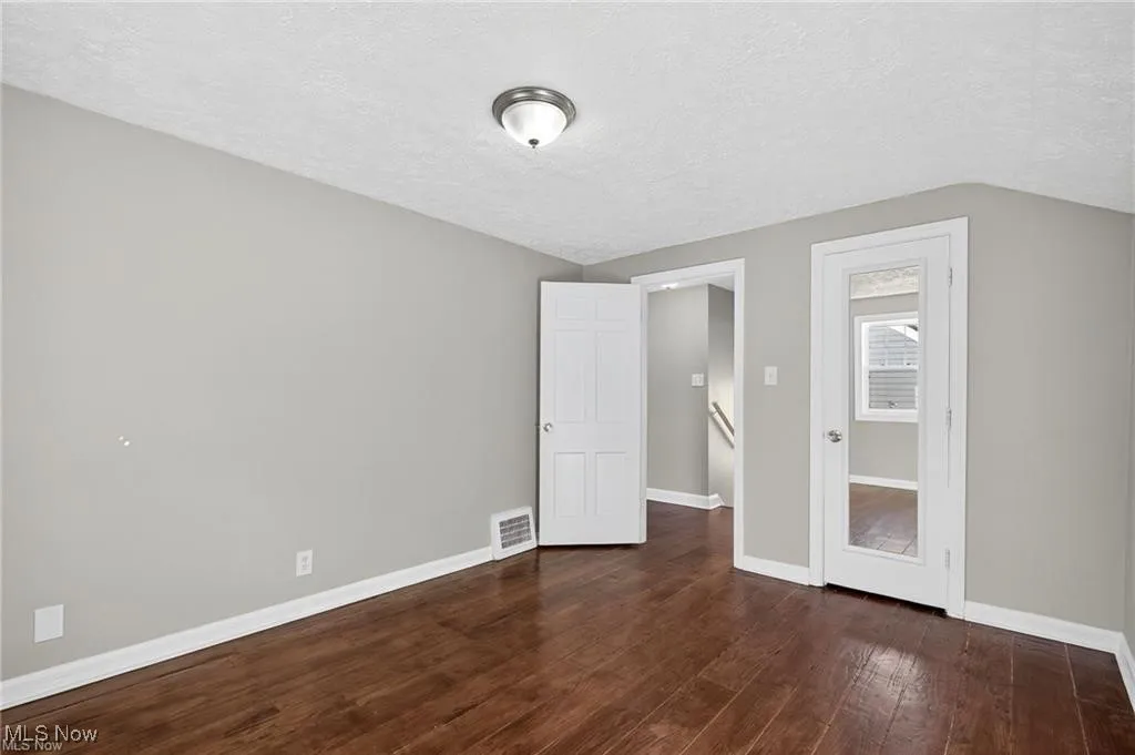 Unfurnished bedroom featuring a textured ceiling and dark wood-style floors