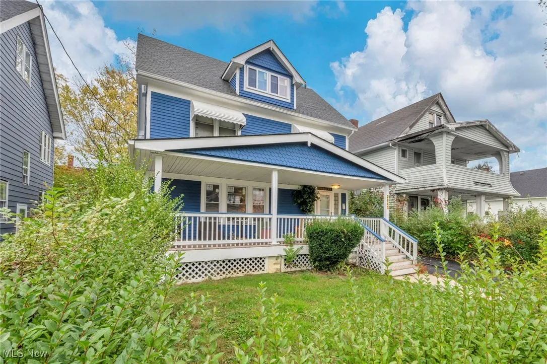 View of front of home featuring covered porch, a front lawn, and roof with shingles