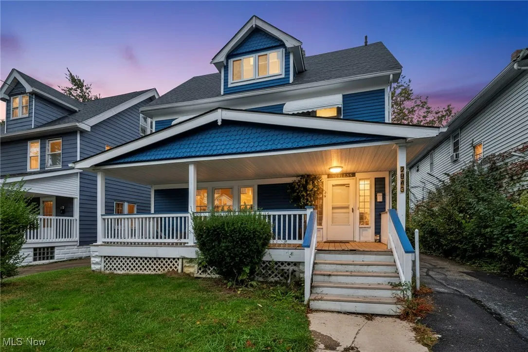 View of front of house with covered porch, a front lawn, and roof with shingles