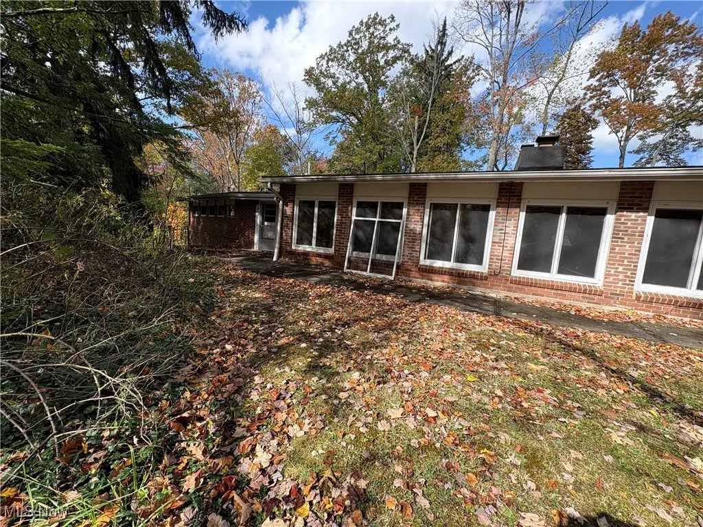 Back of house featuring brick siding and a chimney