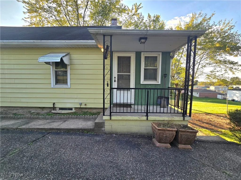 View of front of home with covered porch, a chimney, and a front yard