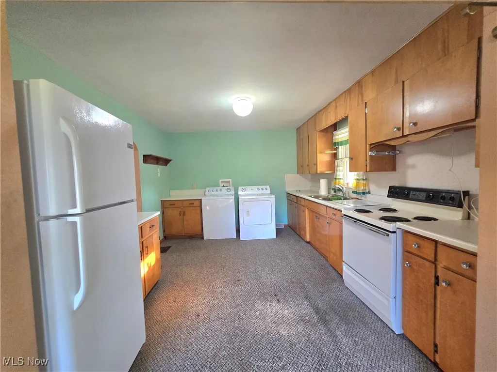 Kitchen featuring white appliances, light countertops, brown cabinets, independent washer and dryer, and open shelves
