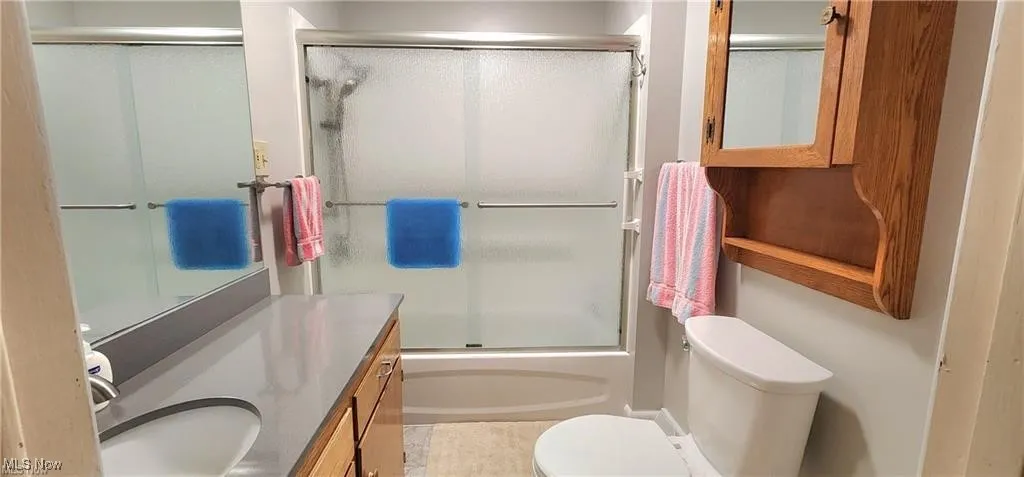 Full bathroom featuring vanity, combined bath / shower with glass door, and toilet