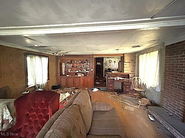 Living area featuring healthy amount of natural light, wood finished floors, wood walls, and brick wall