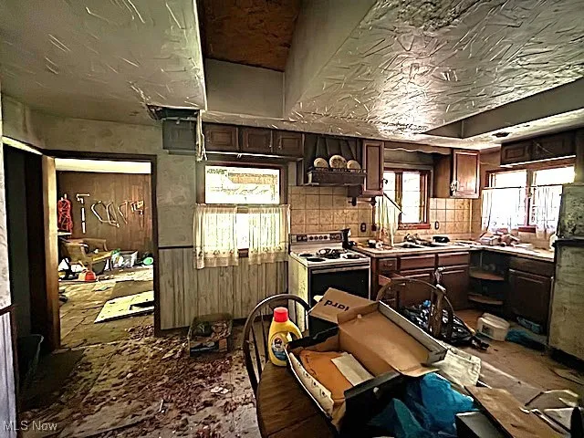 Kitchen with dark brown cabinets, white range with electric stovetop, and light countertops