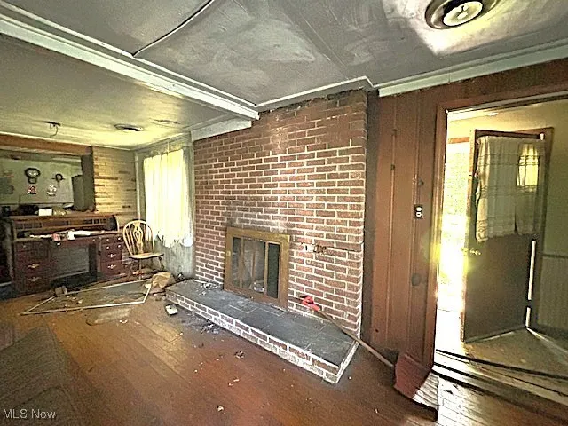 Unfurnished living room with wooden walls, wood-type flooring, and a fireplace