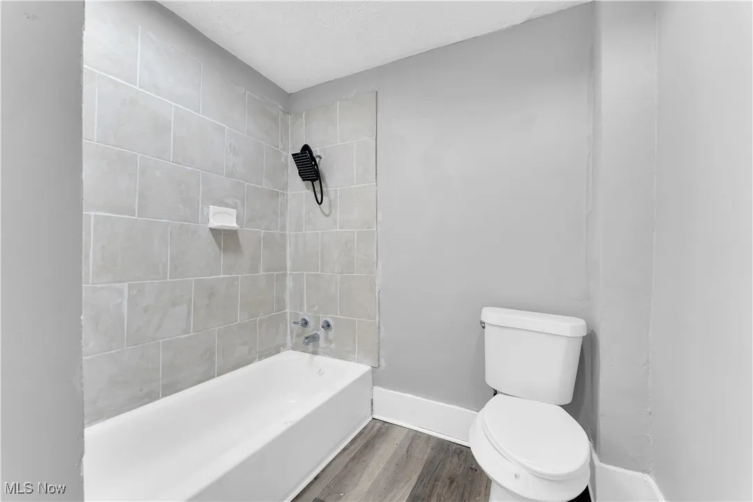 Full bath with tub / shower combination, wood finished floors, and a textured ceiling