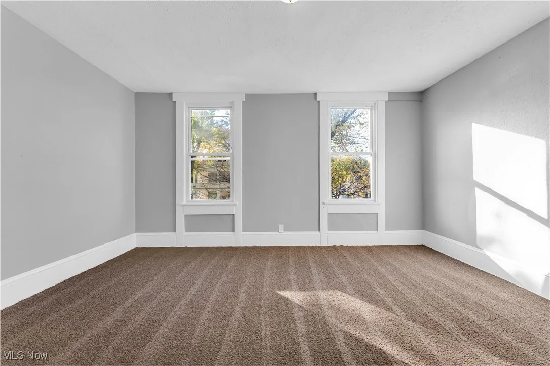 Carpeted spare room featuring baseboards