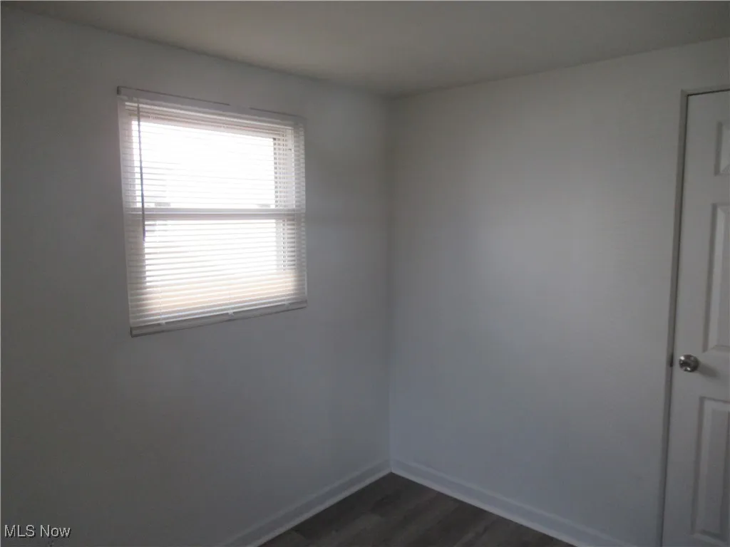 Empty room with dark wood finished floors and baseboards