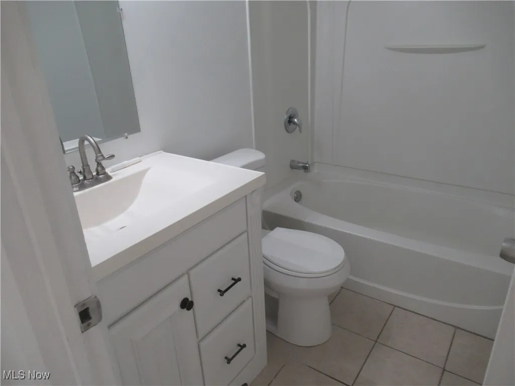 Bathroom with light tile patterned flooring, vanity, and shower / tub combination