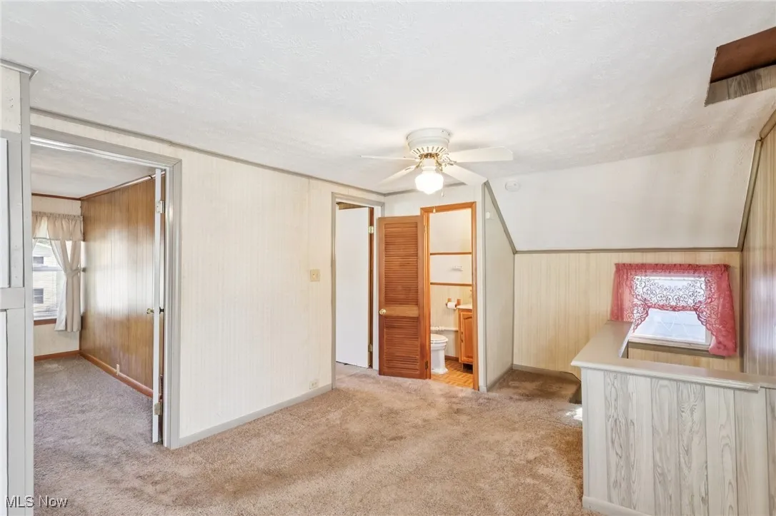 Bonus room with light colored carpet, a textured ceiling, and a ceiling fan