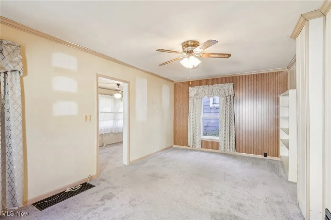 Unfurnished room featuring ornamental molding, carpet floors, and a ceiling fan