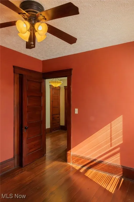 Bedroom with a textured ceiling, dark wood-style floors, and ceiling fan