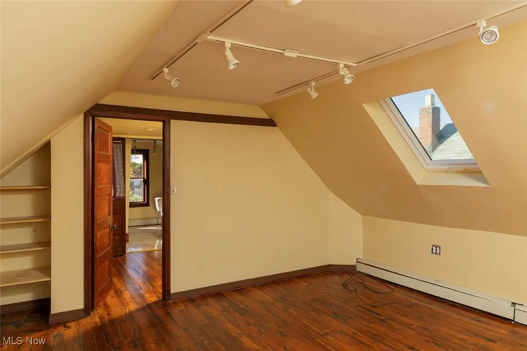 Bonus room with a skylight, dark wood-style flooring, lofted ceiling, and a baseboard radiator