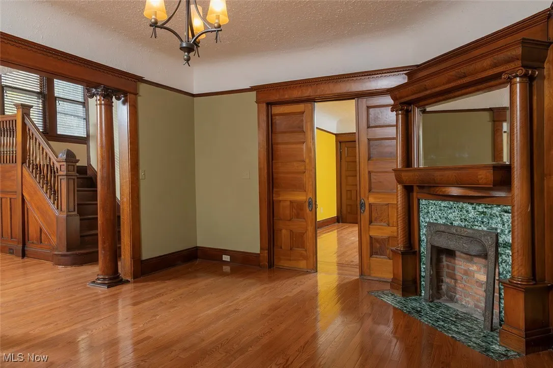living room with a textured ceiling, hardwood / wood-style flooring, stairs, a chandelier, and a high end decorative fireplace