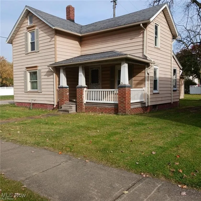 View of front of home with covered porch, a front yard, and a chimney