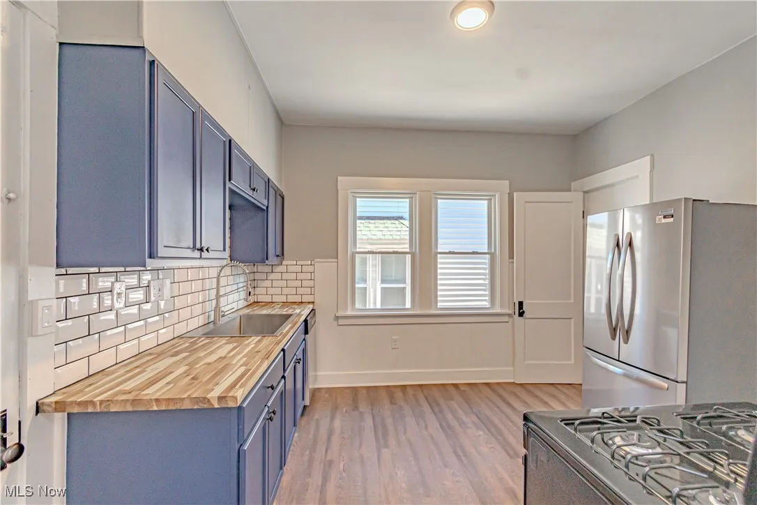 Kitchen featuring wooden counters, blue cabinetry, appliances with stainless steel finishes, light wood finished floors, and tasteful backsplash