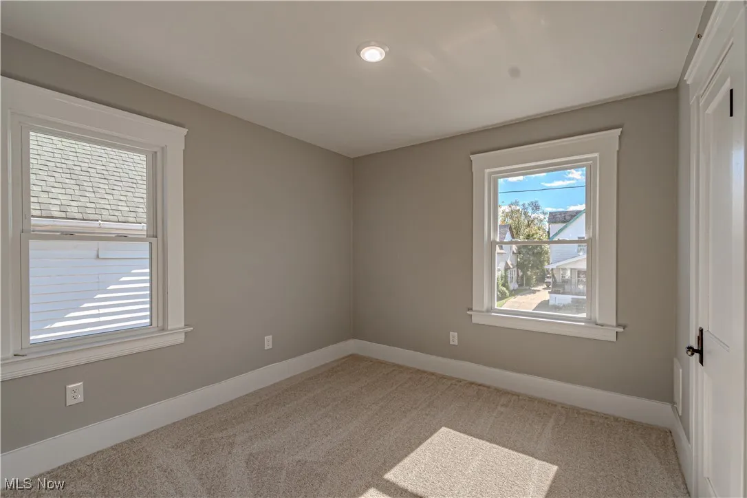 Unfurnished room featuring baseboards and light colored carpet